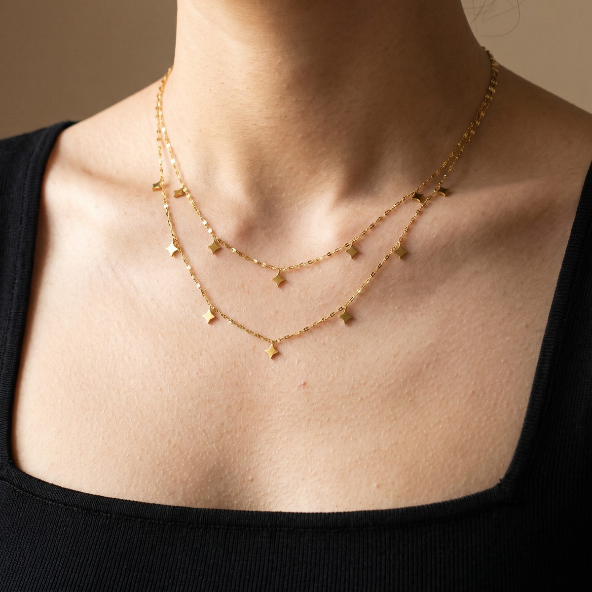 Layered gold tone necklace with star charms, worn