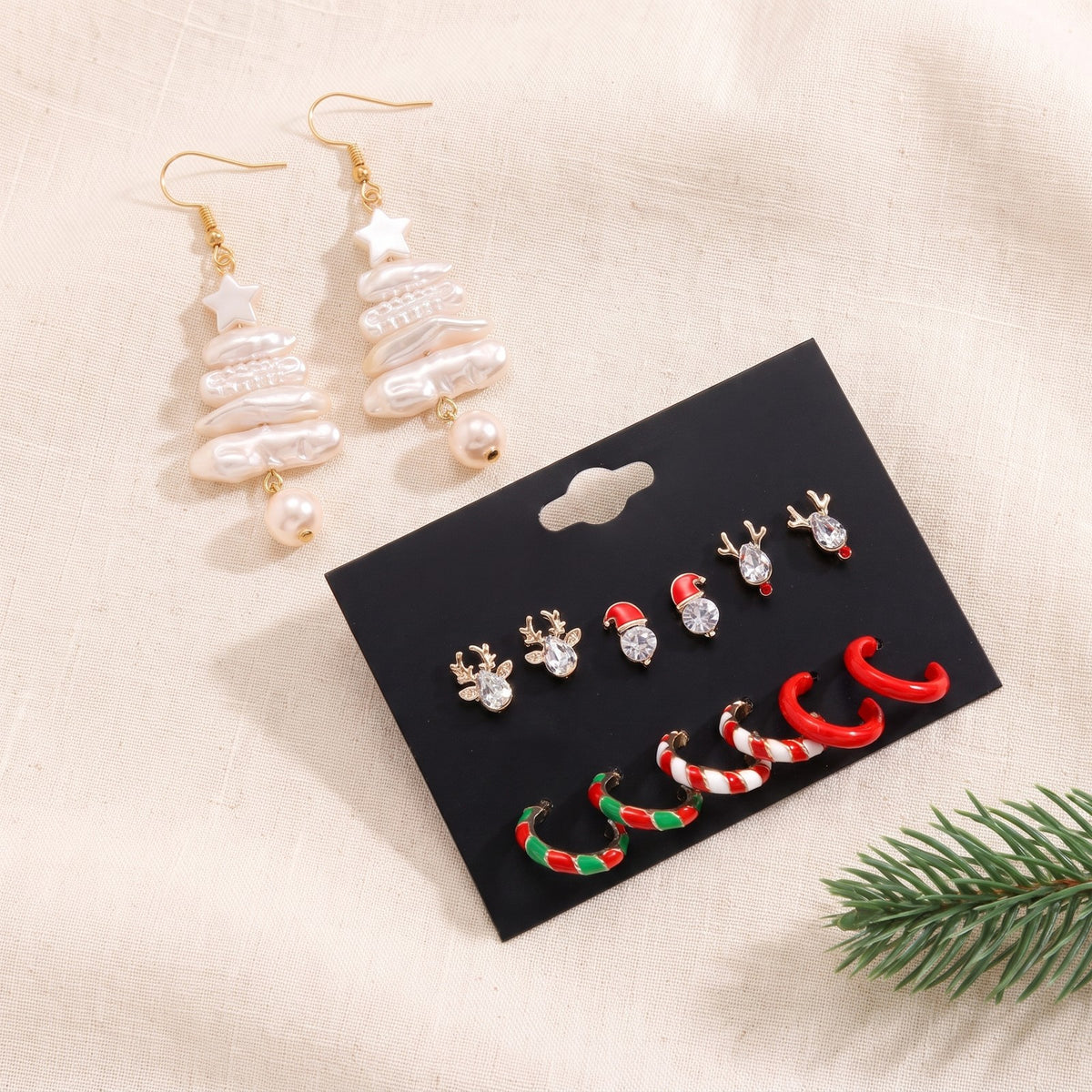 Christmas tree earrings on ivory linen beside the Christmas earring card