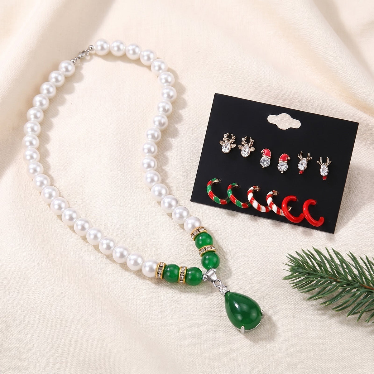 Faux pearl necklace on ivory linen beside the Christmas earring card