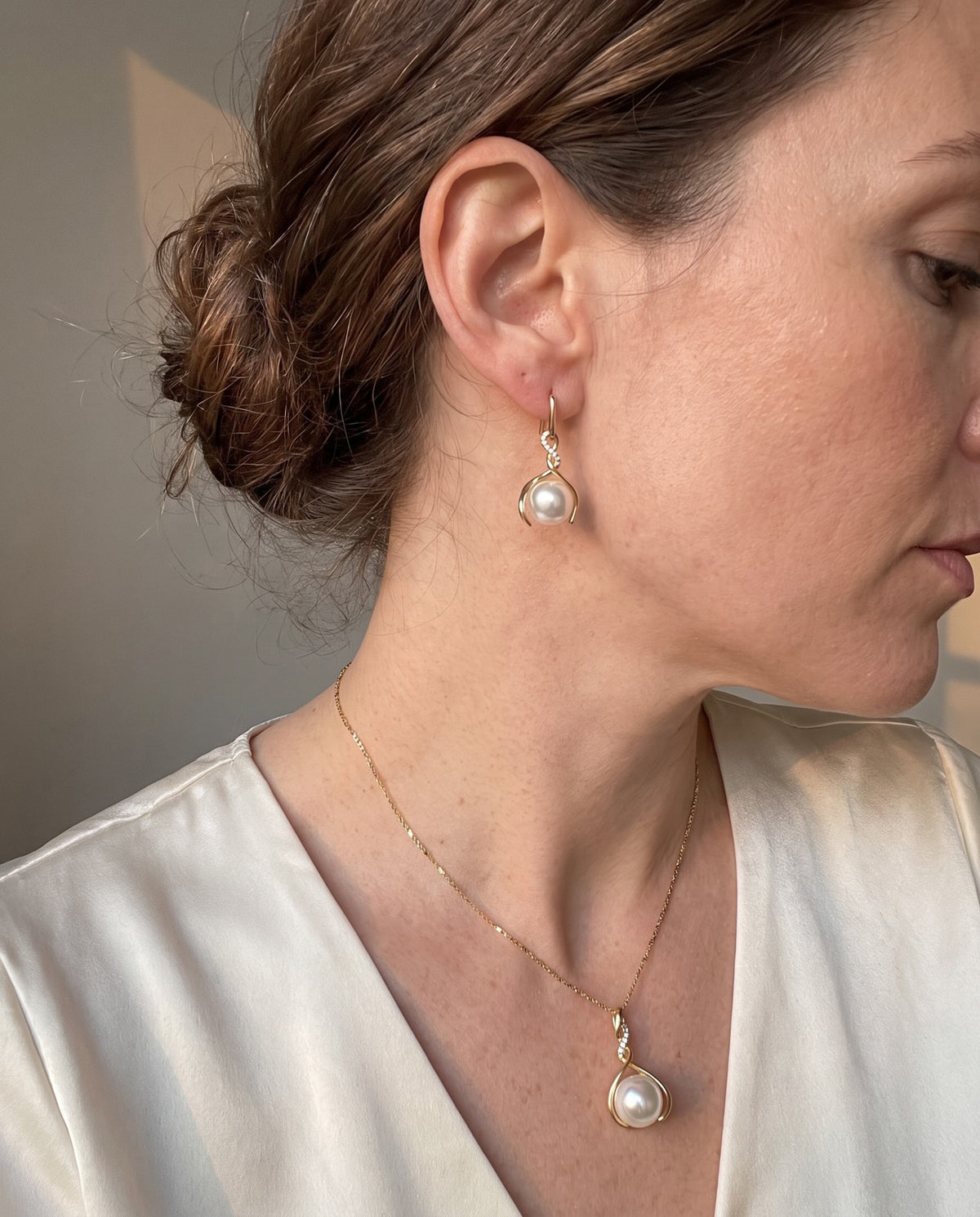 The faux pearl pendant and a matching drop earring worn