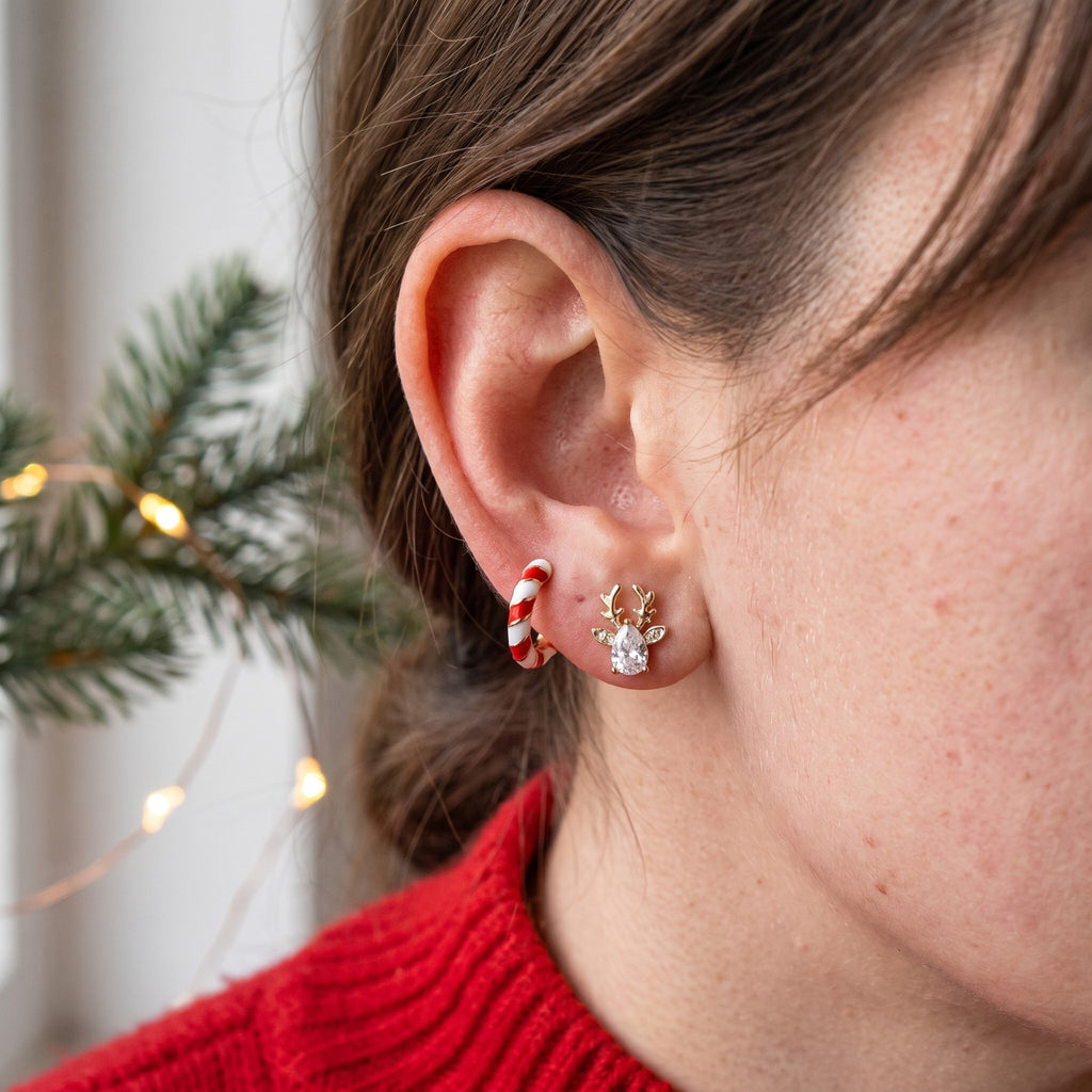 A reindeer stud and a red and white striped hoop from the Christmas set, worn