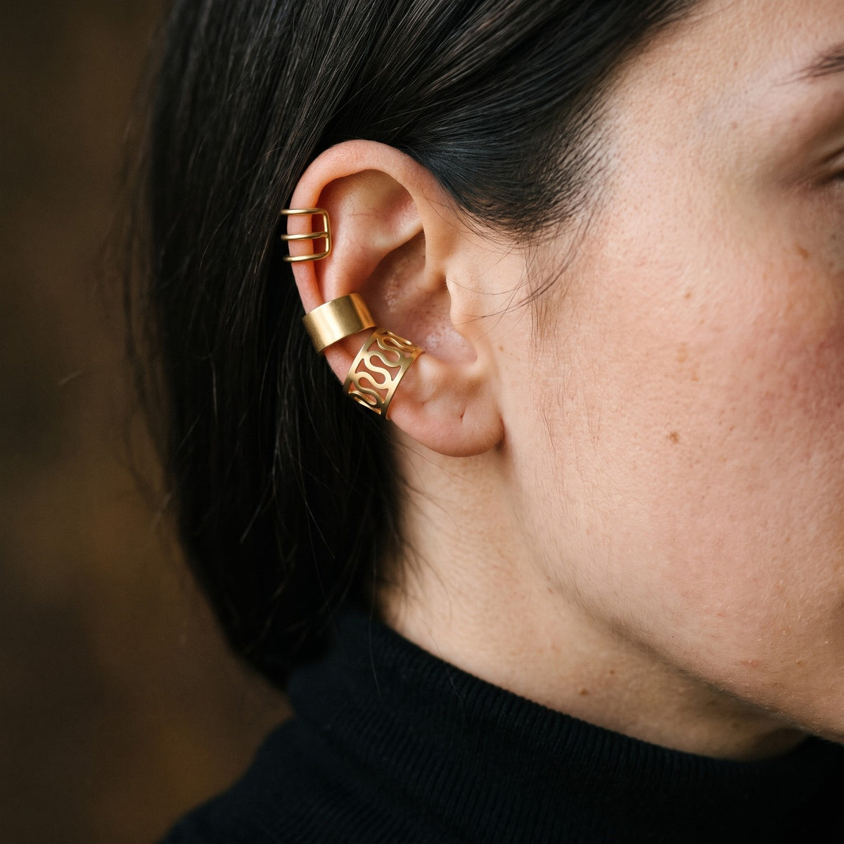 Three gold tone ear cuffs worn on the rim of the ear