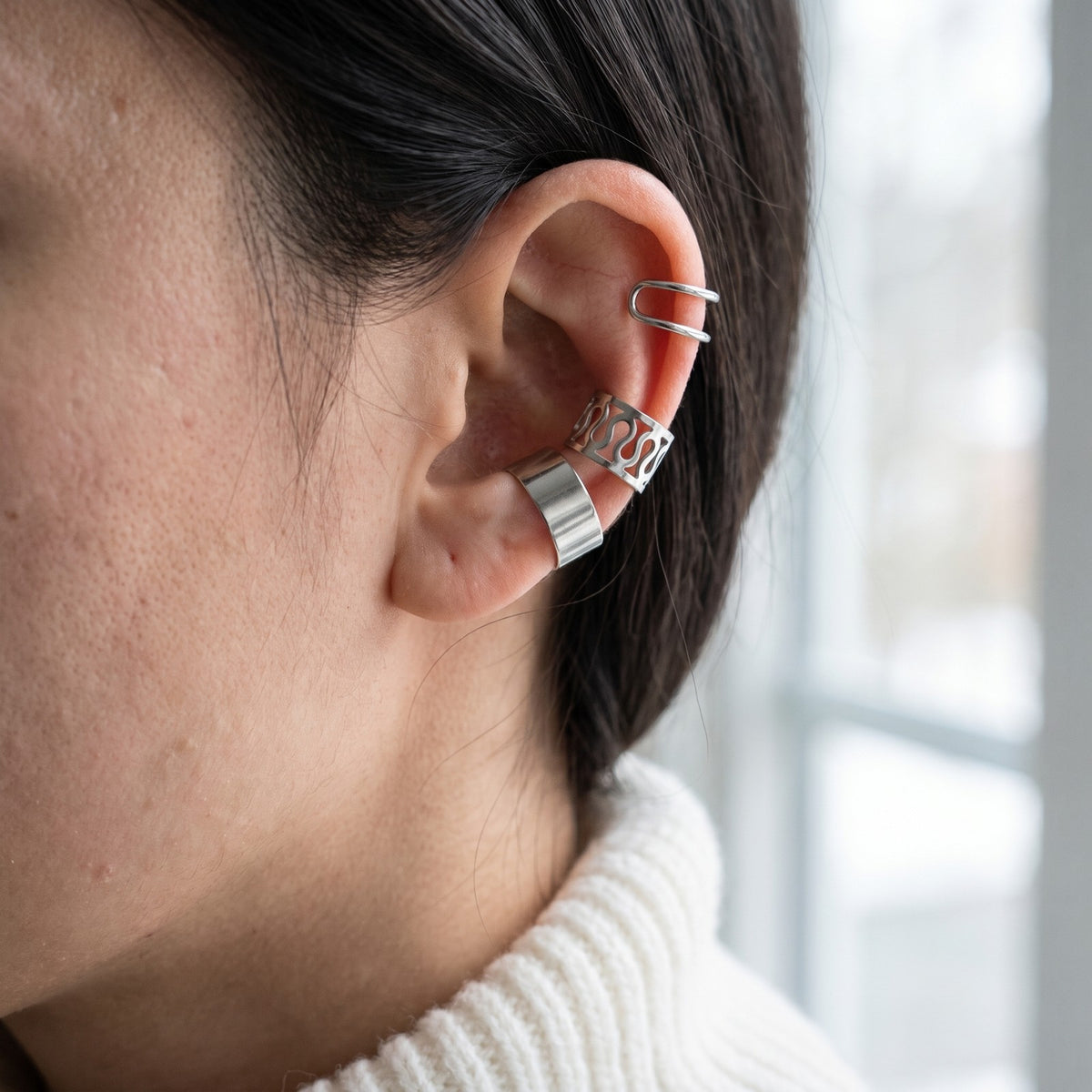 Three silver tone ear cuffs worn on the rim of the ear