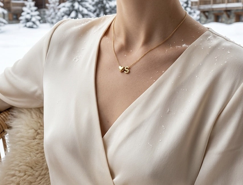 Initial necklace worn with a wrap top, a heart and the letter S