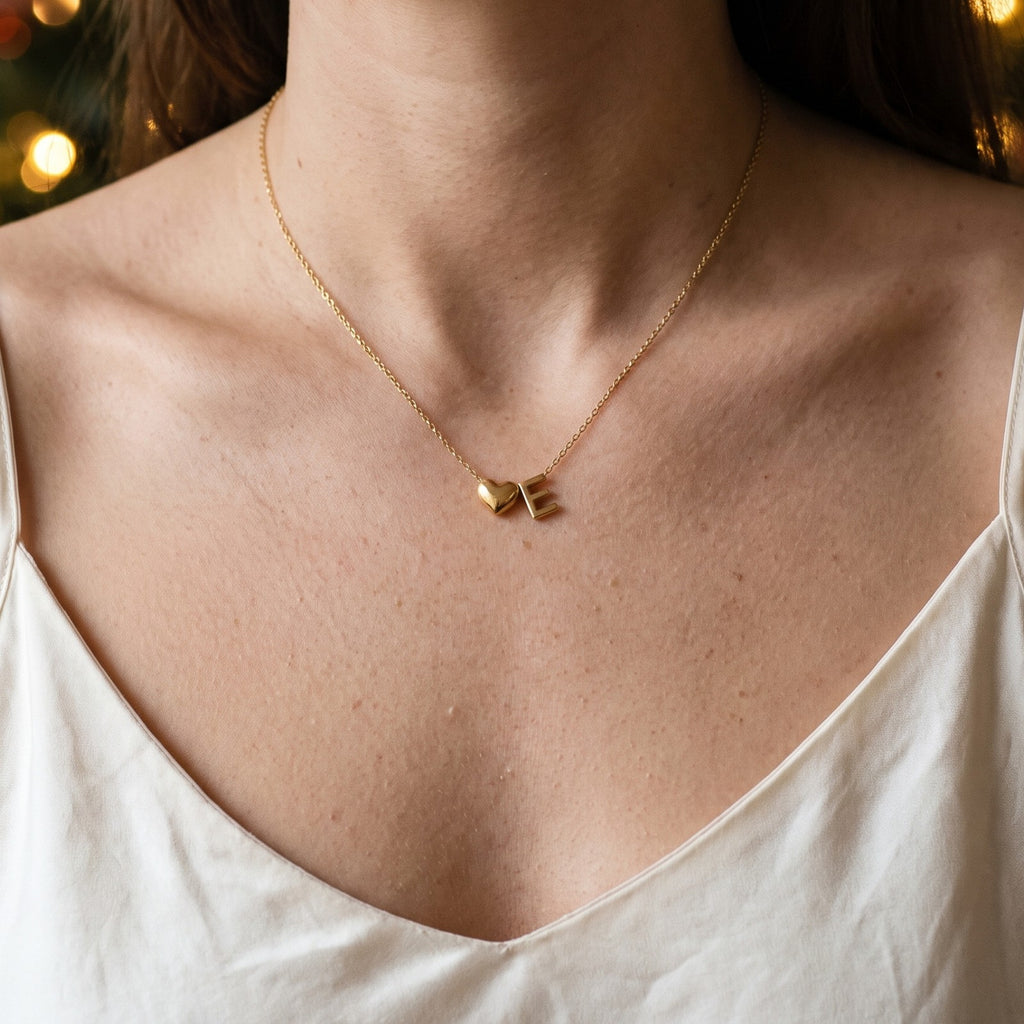 Initial necklace worn, a small heart beside the letter E