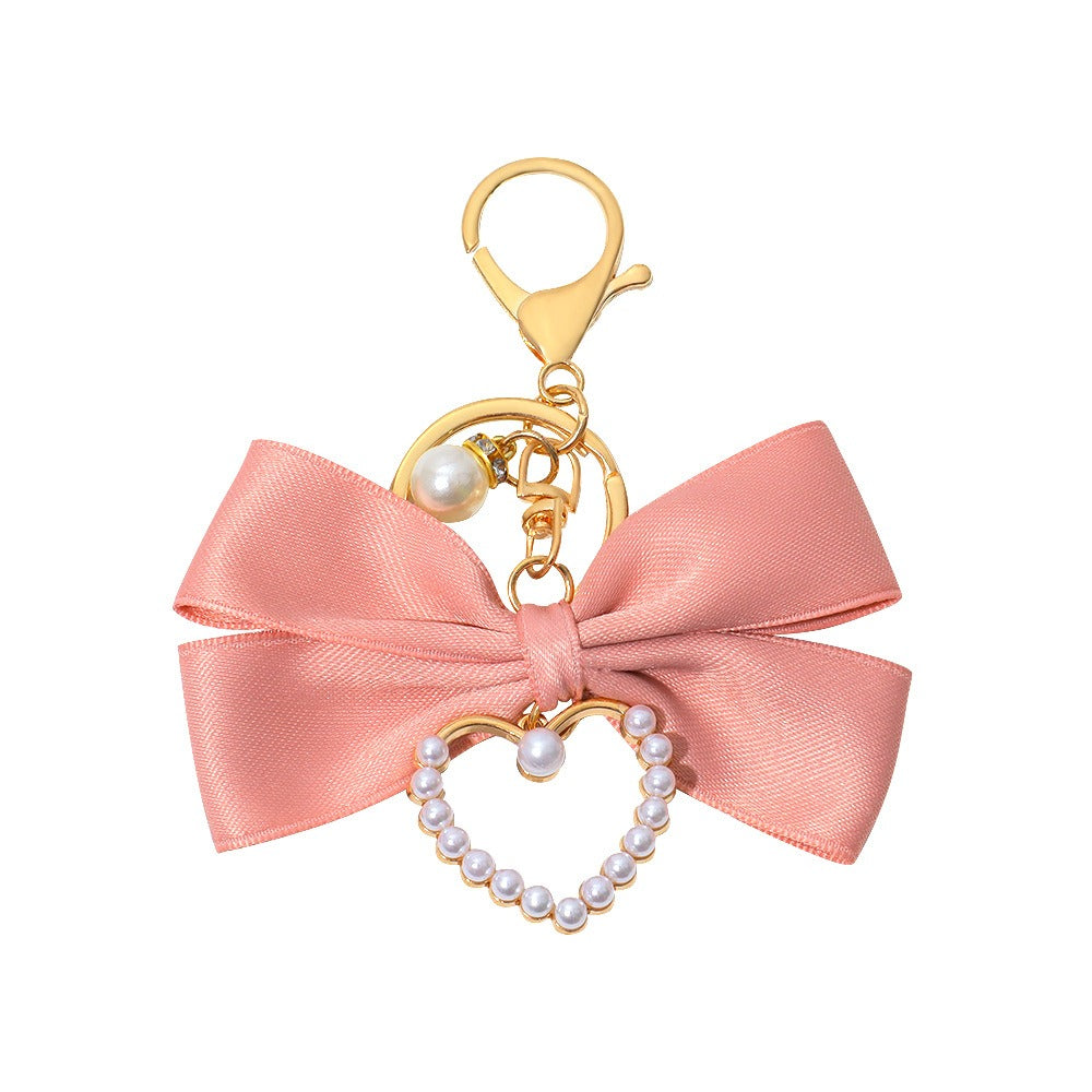 Pink bow bag charm with a faux pearl heart and a gold tone clasp