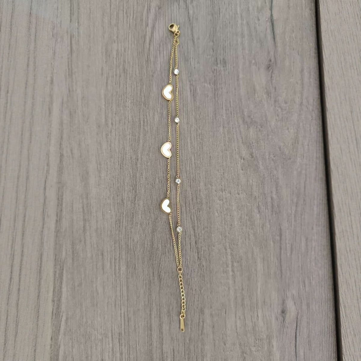 Gold tone two strand heart bracelet laid flat