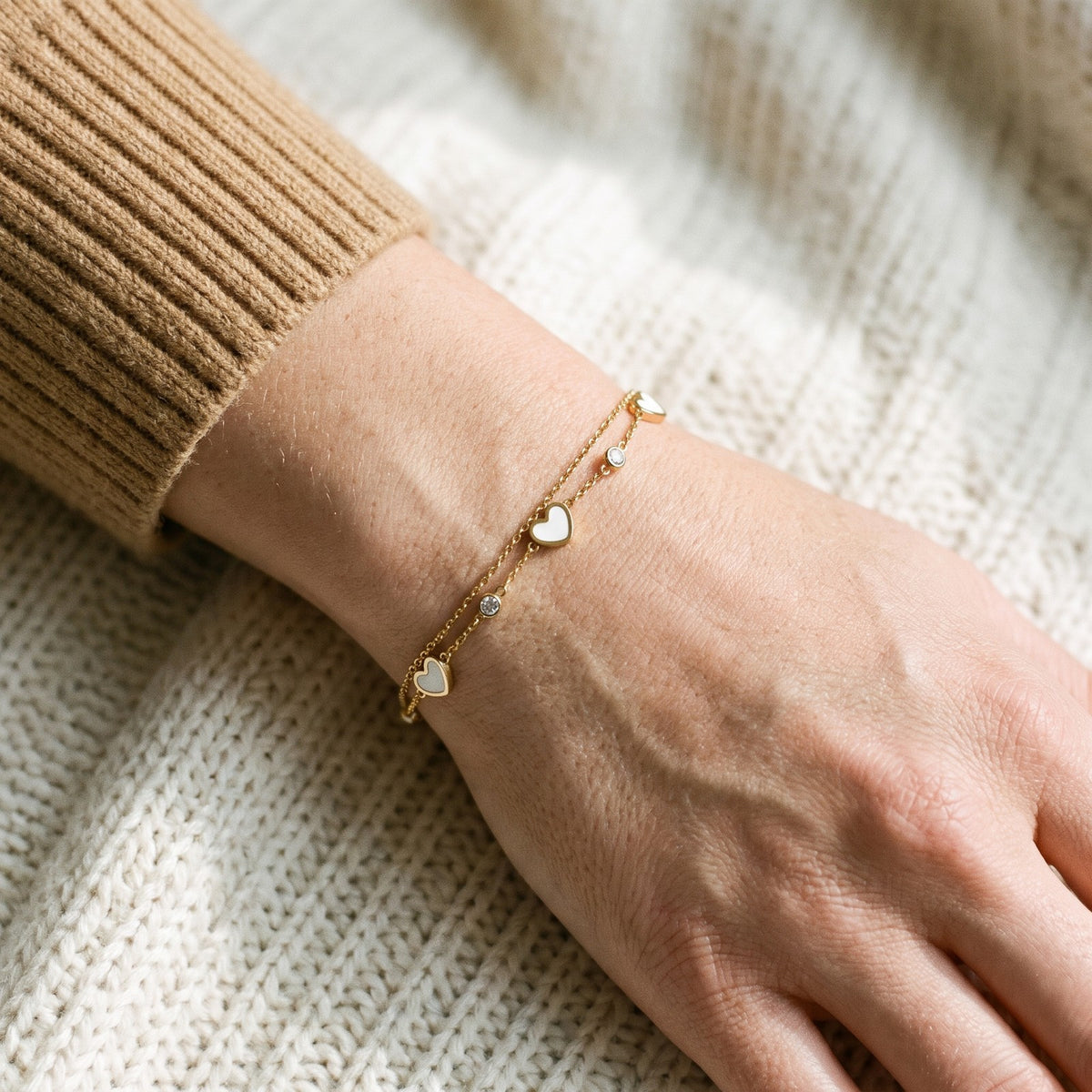 Gold tone two strand heart bracelet worn on the wrist