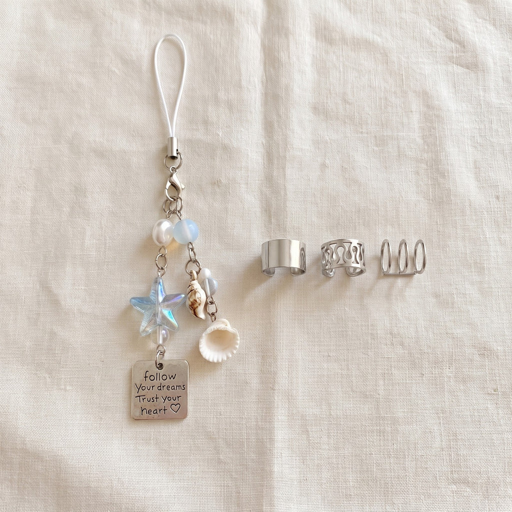 Beaded phone chain on ivory linen beside silver tone ear cuffs