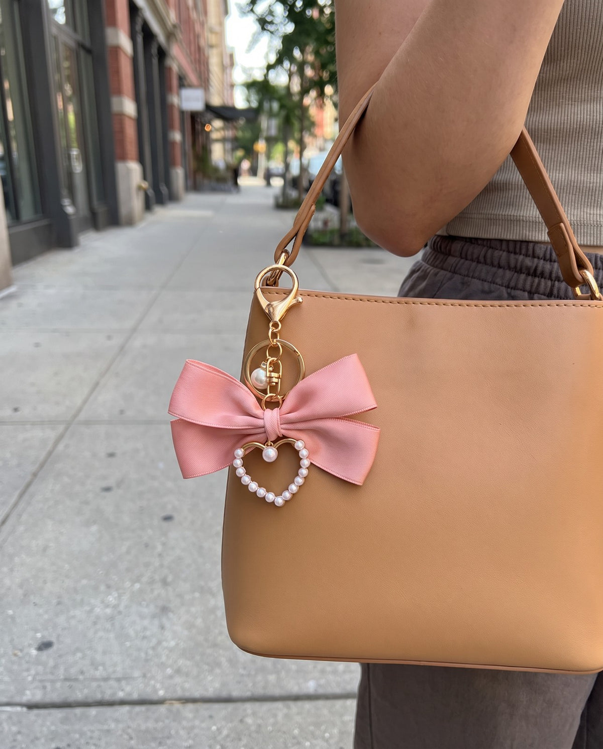 The pink bow charm clipped to a bag handle