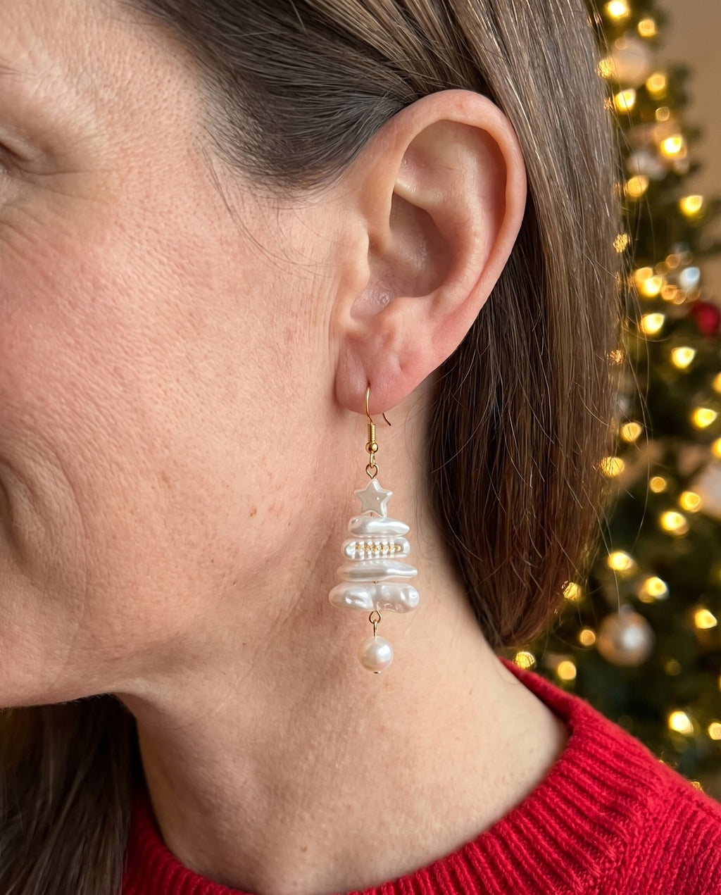 A Christmas tree faux pearl earring worn
