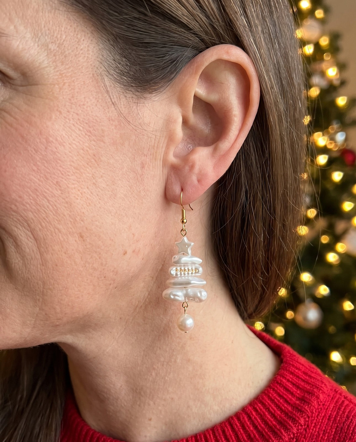 A Christmas tree faux pearl earring worn