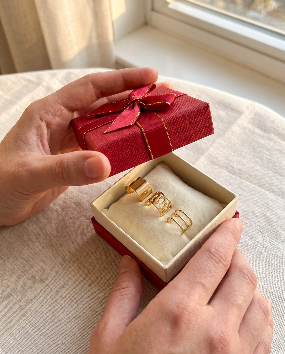 A gift box opened to show three gold tone ear cuffs