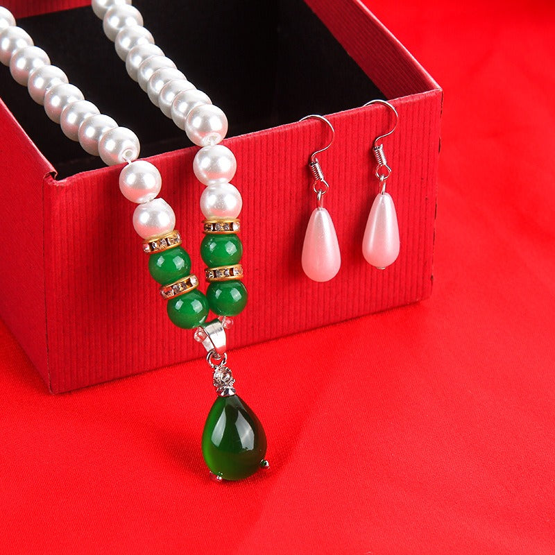 The faux pearl necklace with its green teardrop pendant beside the matching pair of drop earrings