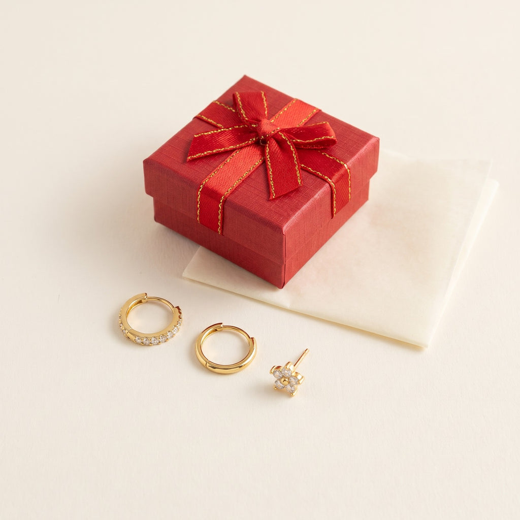 The three Huggie earrings beside a red gift box