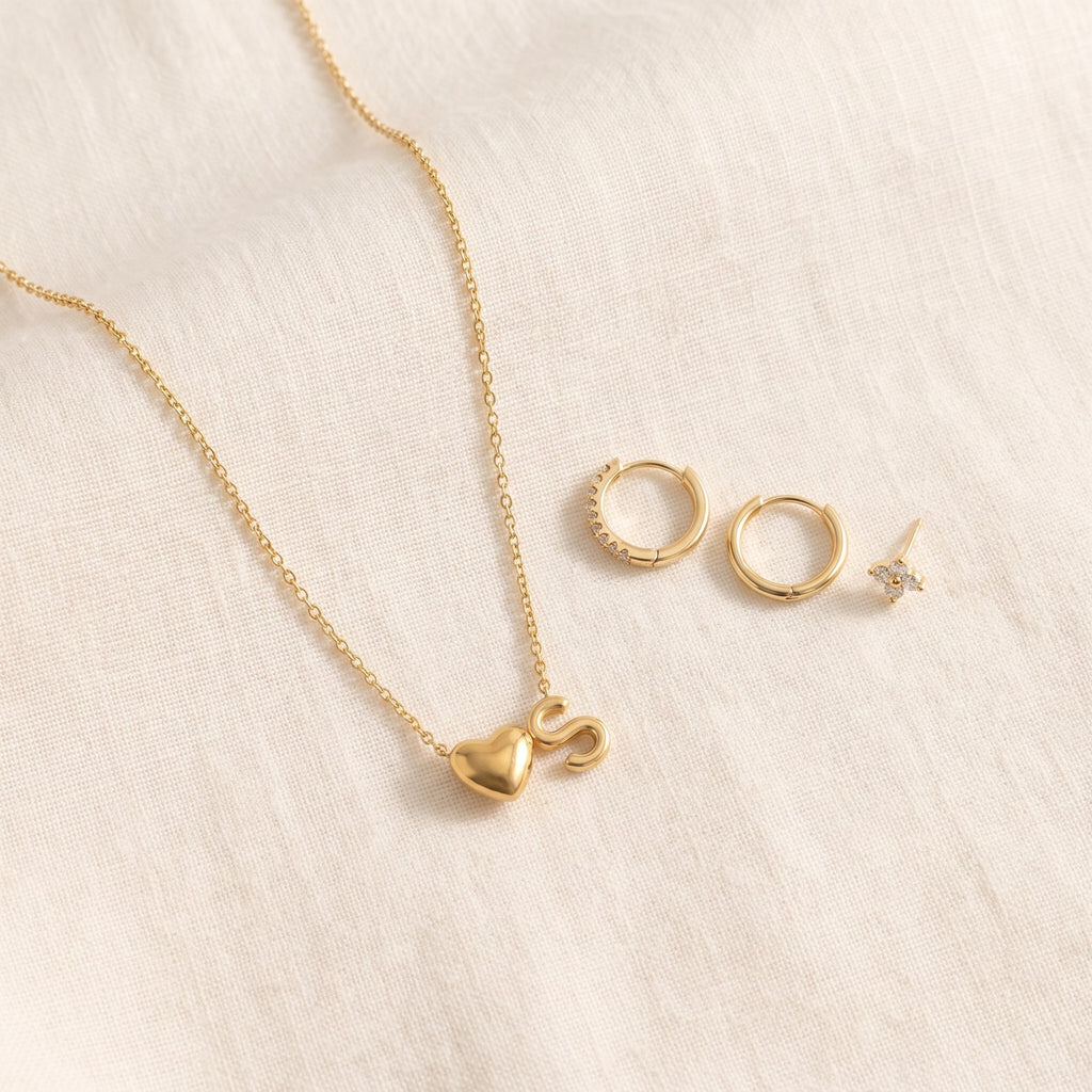 Initial necklace on ivory linen beside the Huggie earrings