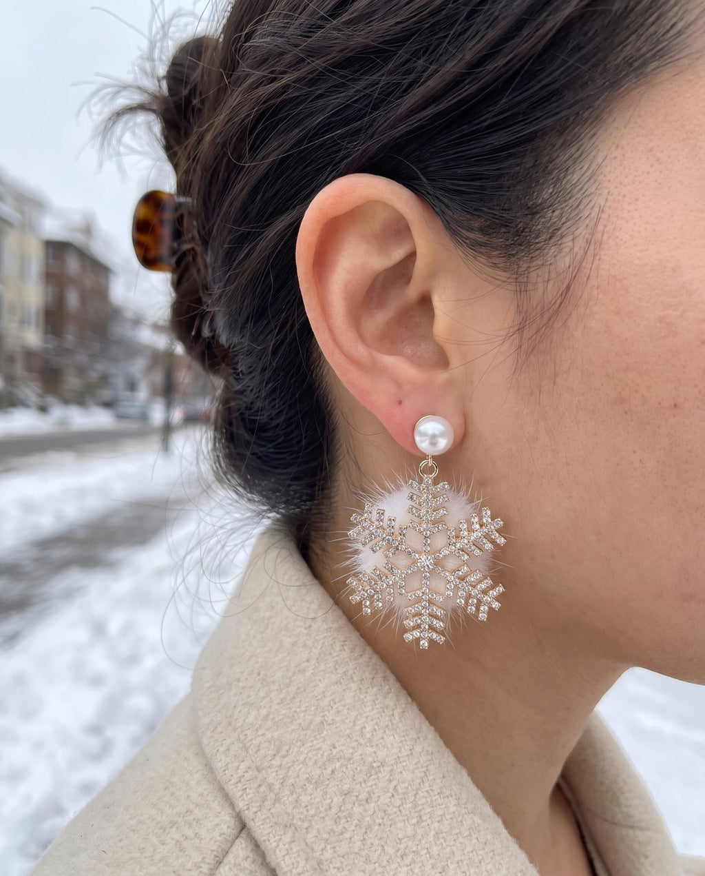 A snowflake earring worn under a faux pearl stud